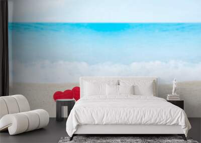 Two red hearts on white sand beach with blurred blue sea Wall mural