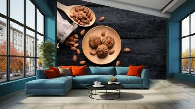 Almond cookies in wooden bowl on old black wooden background Almonds and seeds in freely arranged sacks Delicious organic pastries Wall mural