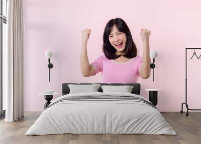 Portrait beautiful young asian woman happy smile with fist up victory gesture expression cheerful her success achievement against pink pastel studio background. Woman day winner celebration concept. Wall mural