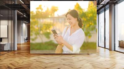 Portrait beautiful young asian woman with smart mobile phone around outdoor street view in a summer day Wall mural