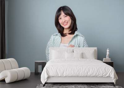 Portrait of young asian woman, teacher or student with digital tablet and pencil, writing, taking notes, doing her homework, standing over green background Wall mural