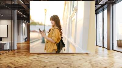 Traveler asian woman in her 30s using smartphone for navigation destination on the urban street at Bangkok, Thailand. Wall mural