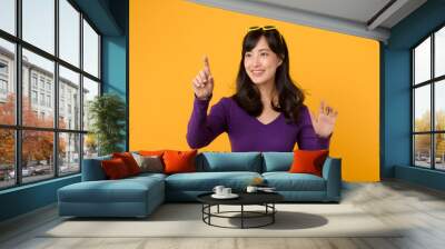 Young Asian 30s businesswoman wearing purple jumper shirt pointing on invisible screen. Wall mural