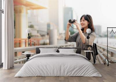 Young Asian woman backpack traveler using a camera in express boat pier on Chao Phraya River in Bangkok. Wall mural