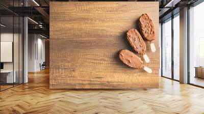 Popsicle, ice cream covered with chocolate on wooden table. Top view. Wall mural