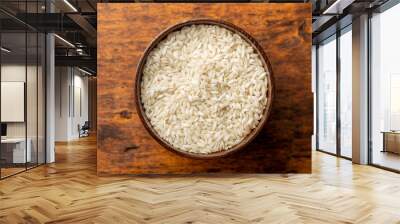 Uncooked Carnaroli risotto rice in bowl on wooden table. Wall mural