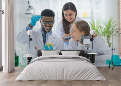 Team of smiling scientist or researcher in laboratory testing cbd oil extracted from a marijuana plant or alternative drug from marijuana leaf plant, organic nature herb in science test. Wall mural