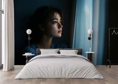 depressed young woman sitting by the window at home, isolated and facing looking  Wall mural