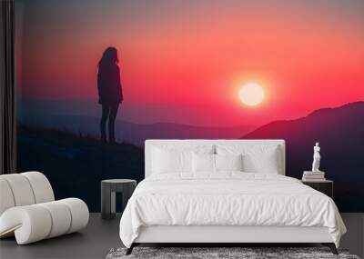 Breathtaking sunset fading behind a majestic mountain range casting a peaceful silhouette of a lone figure standing amidst the tranquil scenery Wall mural