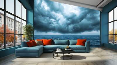 Dramatic storm clouds gathering over the vast moody ocean signaling the approach of an intense turbulent weather system  The ominous Wall mural