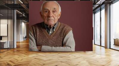 Pensive and thoughtful portrait of an elderly Romanian man wearing a classic sweater vest against a plain plum background with copy space above the subject Wall mural