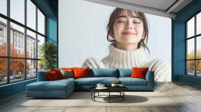 Portrait of a beautiful young Japanese woman with a joyful and happy expression wearing a cozy oversized sweater against a plain white studio background with soft natural lighting Wall mural