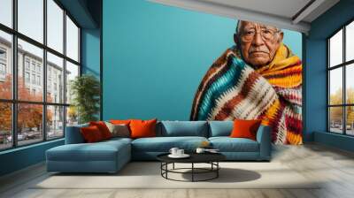 Serene portrait of an elderly Mexican man dressed in a cozy traditional blanket against a plain azure background leaving ample copy space above the full body subject Wall mural