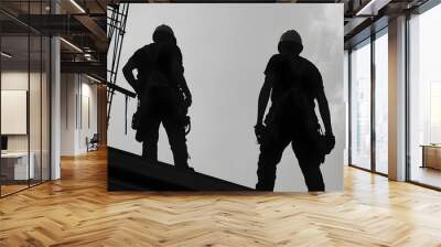 Silhouette of two construction workers wearing protective safety gear and helmets standing on an industrial construction site Wall mural