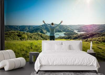 Hiker found a camping site on top of a mountain overlooking a beautiful lake Wall mural