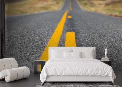 low angle closeup view of yellow dividing and no passing lines and stripes in middle of asphalt road Wall mural