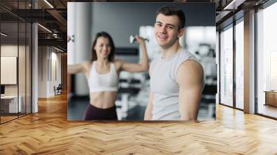 gym after strength exercises for different muscles, work out his body, push-up, squats and abs crunches with the training girl on background. Fitness, healthy and self-control concept. Wall mural