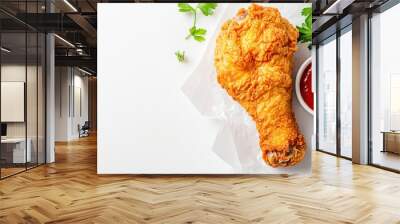 Crispy fried chicken drumstick served with tangy sauce and fresh herbs on white background, perfect for food lovers. Wall mural