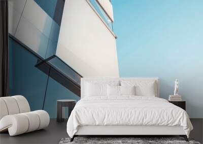 Modern architectural design featuring sleek glass and metal elements under a clear blue sky, showcasing contemporary elegance. Wall mural