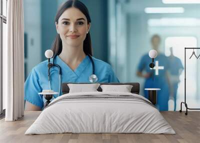 Portrait of a nurse in blue scrubs holding a clipboard, smiling confidently in a hospital corridor. Wall mural