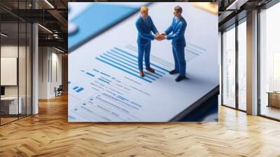 Two miniature business men shaking hands on a clipboard filled with financial charts and reports. Wall mural