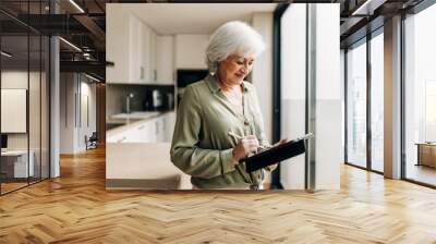 Mature woman signing on a digital tablet at home Wall mural