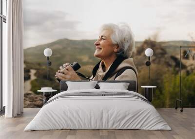 Senior woman looking at the view from a hilltop Wall mural