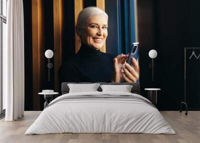 Working the modern way: Senior woman using smartphone for business Wall mural