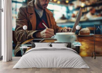 Casual man writing in notebook at a cafe with cup of coffee Wall mural