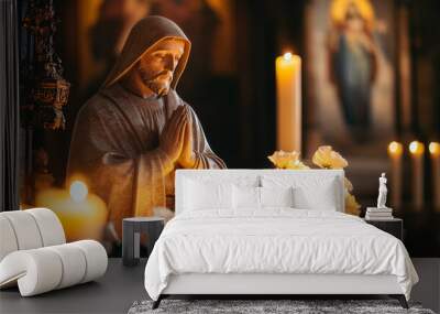 A statue of a man praying in front of candles Wall mural