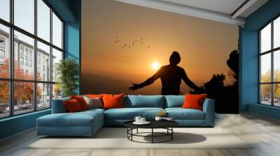 Man with open arms at sunset conveying a sense of freedom. Wall mural