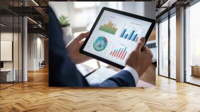 Analyzing Financial Data on Tablet. Close-up of a professional analyzing complex financial data and graphs on a digital tablet. Wall mural