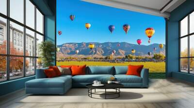 A large group of hot air balloons are flying in the sky over a grassy field Wall mural