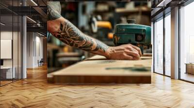 A man with tattoos on his hands is carving a design into a piece of wood Wall mural