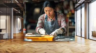 A woman is working in a kitchen, wearing an apron and gloves Wall mural