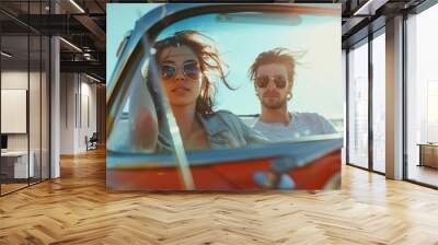 Carefree young couple driving a vintage car with the wind blowing through their hair on a sunny day Wall mural