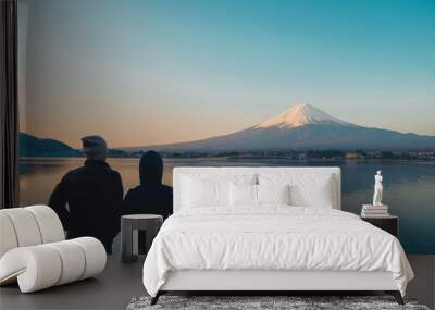 Couple traveler standing and looking Beautiful Mount Fuji with snow capped in the morning sunrise at Lake kawaguchiko, Japan. landmark and popular for tourist attractions. travel concept Wall mural