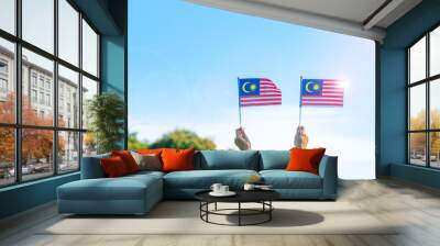 hand holding Malaysia flag on blue sky background. September Malaysia national day and August Independence day Wall mural