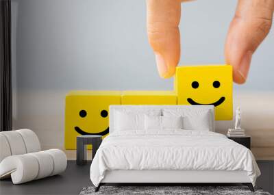 Hand holding smile face symbol on yellow wooden cube blocks. Emotion, Service rating, ranking, customer review, satisfaction and feedback concept Wall mural