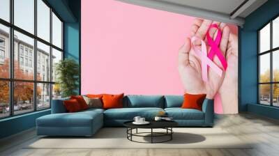 October Breast Cancer Awareness month, adult Woman hand holding Pink Ribbon on pink background for supporting people living and illness. International Women, Mother and World cancer day concept Wall mural