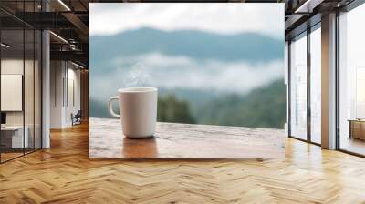 White mug of hot coffee or tea on wooden table in the morning with mountain and nature background Wall mural