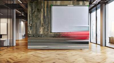 Blank white billboard on wall. In the foreground a blurred passing red car on the street. Wall mural