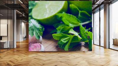 Green fruit and vegetable - wooden board with green food  ingredients: garlic, avocado, lime, mint, cilantro, leek, green chili peppers. Wall mural