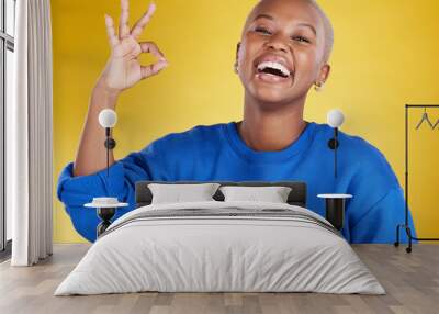 Portrait, laughing and black woman with ok sign in studio isolated on a yellow background. Success, emoji face and happy, comic and funny female with hand gesture for okay, support or perfection. Wall mural