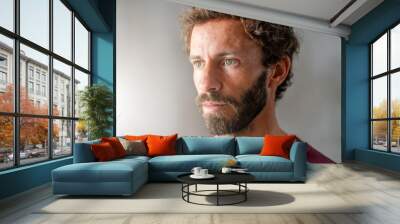 Portrait of a attractive handsome young man with beard looking outside of the window. Confident and serious look close-up photo.  Wall mural