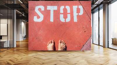 A man in bare feet stops at a stop mark painted on the ground. Wall mural