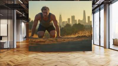 Caucasian male jogger in athletic wear catches his breath while on a trail with a city skyline view during golden hour Wall mural