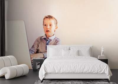 Child working business on his white laptop with surprise face. Wall mural