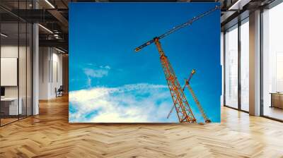 Detail of tower cranes isolated blue sky background. Wall mural