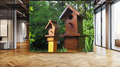 Two decorative wooden birdhouses on the background of park green plants. Closeup photo Wall mural